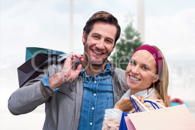 Composite image of smiling couple with shopping bags