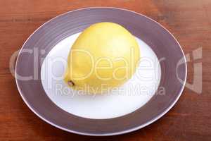 Whole lemon on a grey plate on wooden background