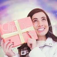 Composite image of portrait of a happy brunette holding gift