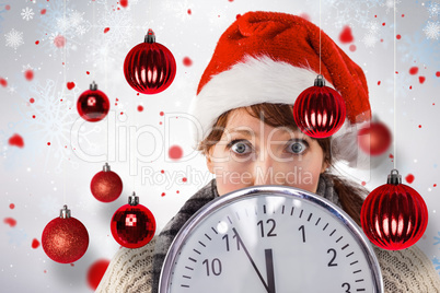 Composite image of woman holding a large clock
