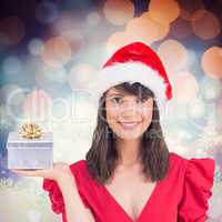 Composite image of festive brunette holding a gift