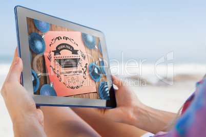 Composite image of woman sitting on beach in deck chair using ta