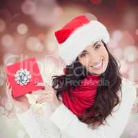 Composite image of joyful brunette presenting christmas gift