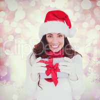 Composite image of festive brunette in santa hat holding gift