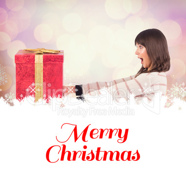 Composite image of surprised brunette holding a gift