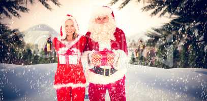 Composite image of santa and mrs claus smiling at camera offerin