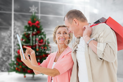 Composite image of couple with shopping bags and tablet