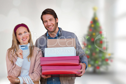 Composite image of smiling couple showing credit card and carryi