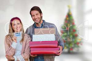 Composite image of smiling couple showing credit card and carryi