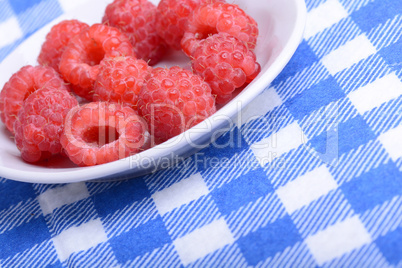 Fresh raspberries. Closeup of fruits on a white plate