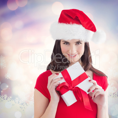 Composite image of festive brunette holding gift