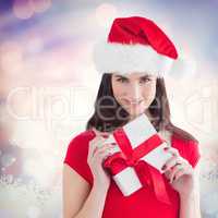 Composite image of festive brunette holding gift