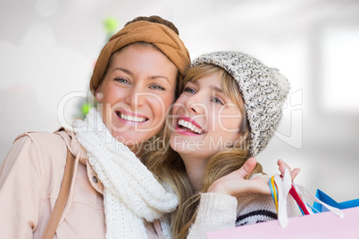 Composite image of smiling women looking at camera with shopping