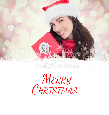 Composite image of smiling brunette holding christmas gifts