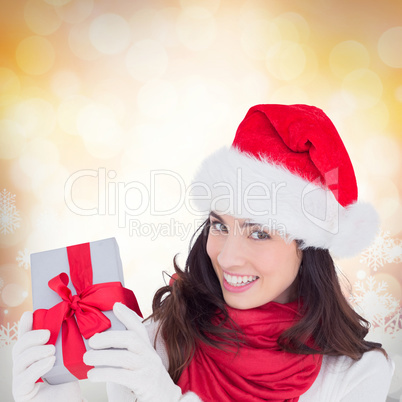 Composite image of excited brunette in santa hat showing gift