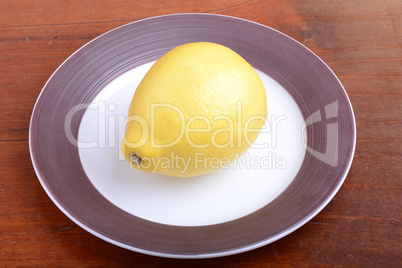 Whole lemon on a grey plate on wooden background