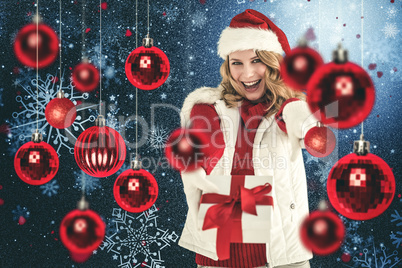 Composite image of festive blonde holding christmas gift and poi