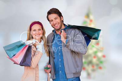 Composite image of smiling couple with shopping bags in front of