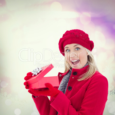 Composite image of festive blonde holding red gift