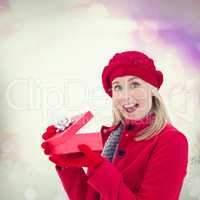 Composite image of festive blonde holding red gift