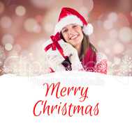 Composite image of attractive woman wearing santa hat with gift