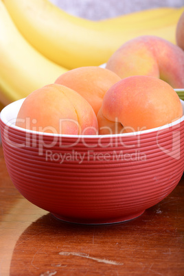 bananas and apricots on red plate, close up