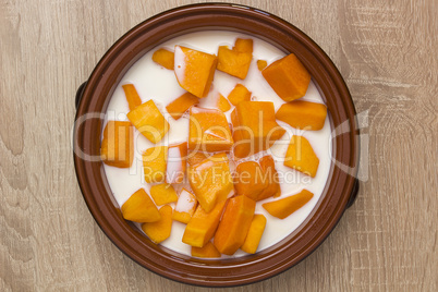 Pumpkin sliced in clay pot with milk