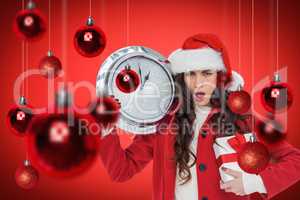 Composite image of surprised brunette holding a clock and gift