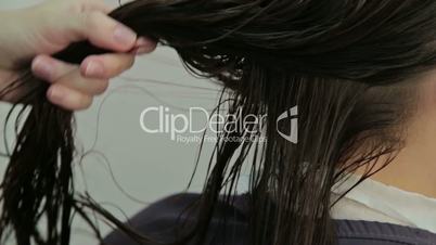 Hairdresser combing client's wet hair in salon