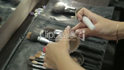 Different cosmetic brushes for makeup with woman hands