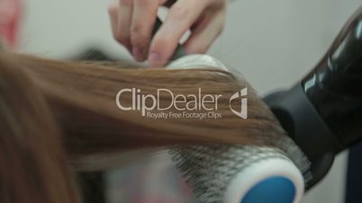 Hairstylist with brush and dryer. hairdresser drying hair of female client. Woman in hairdressing beauty salon.