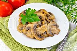 Champignons fried in plate with parsley on light board
