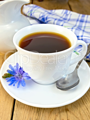 Chicory drink in white cup with spoon and milkman on board