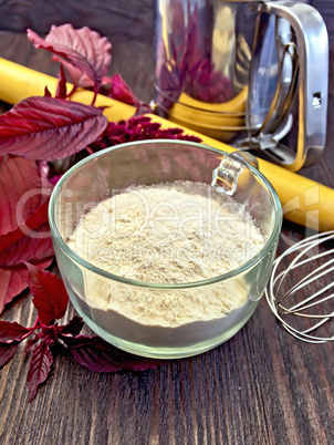 Flour amaranth in glass cup on board with rolling pin