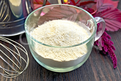Flour amaranth in glass cup with sieve on board