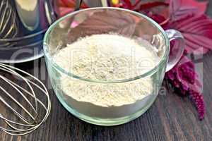 Flour amaranth in glass cup with sieve on board