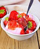 Ice cream strawberry in white bowl with spoon on board