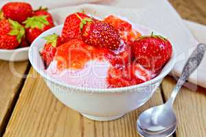 Ice cream strawberry in white bowl and spoon on board