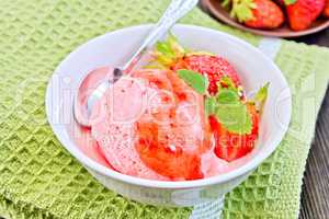 Ice cream strawberry with syrup and spoon in bowl on board