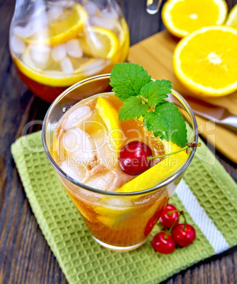 Lemonade with cherry in glassful and pitcher on board