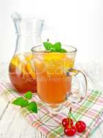 Lemonade with cherry in wineglass and pitcher on board