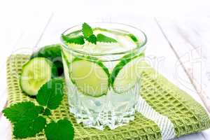 Lemonade with cucumber and mint in glassful on board