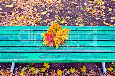 Maple leaves on green bench