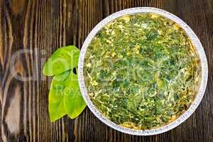 Pie celtic with spinach in form of foil on board