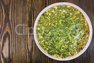Pie celtic with spinach in form of foil on table