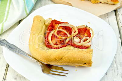 Pie with onions and tomatoes in white plate on board