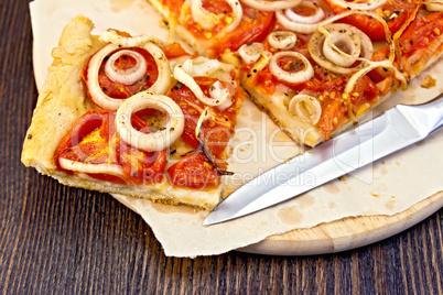 Pie with onions and tomatoes on paper and board