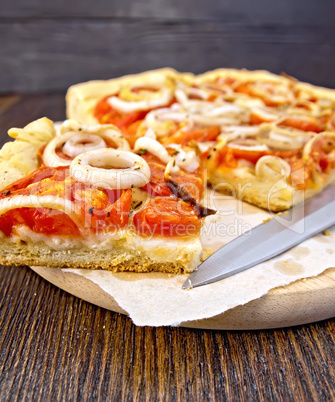 Pie with onions and tomatoes on paper with knife