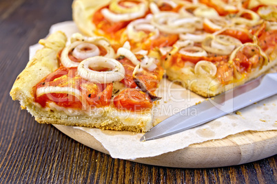 Pie with onions and tomatoes on parchment