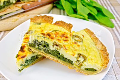 Pie with spinach in plate on fabric